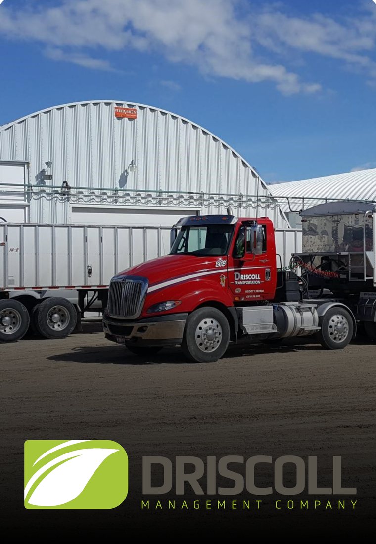 A red Driscoll truck in front of a white arched storage building